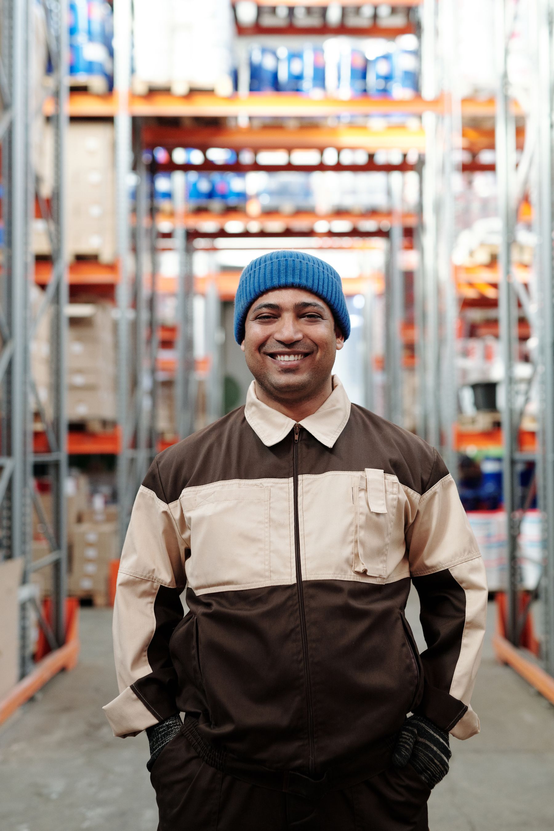 Warehouse worker in a blue beanie standing between storage racks
